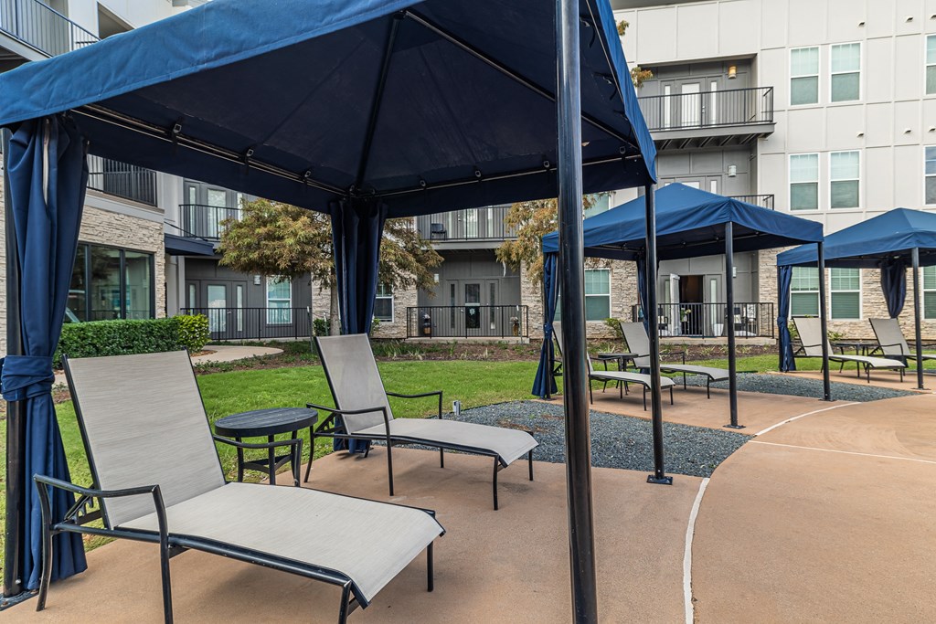 a patio with chairs and umbrellas in front of an apartment building