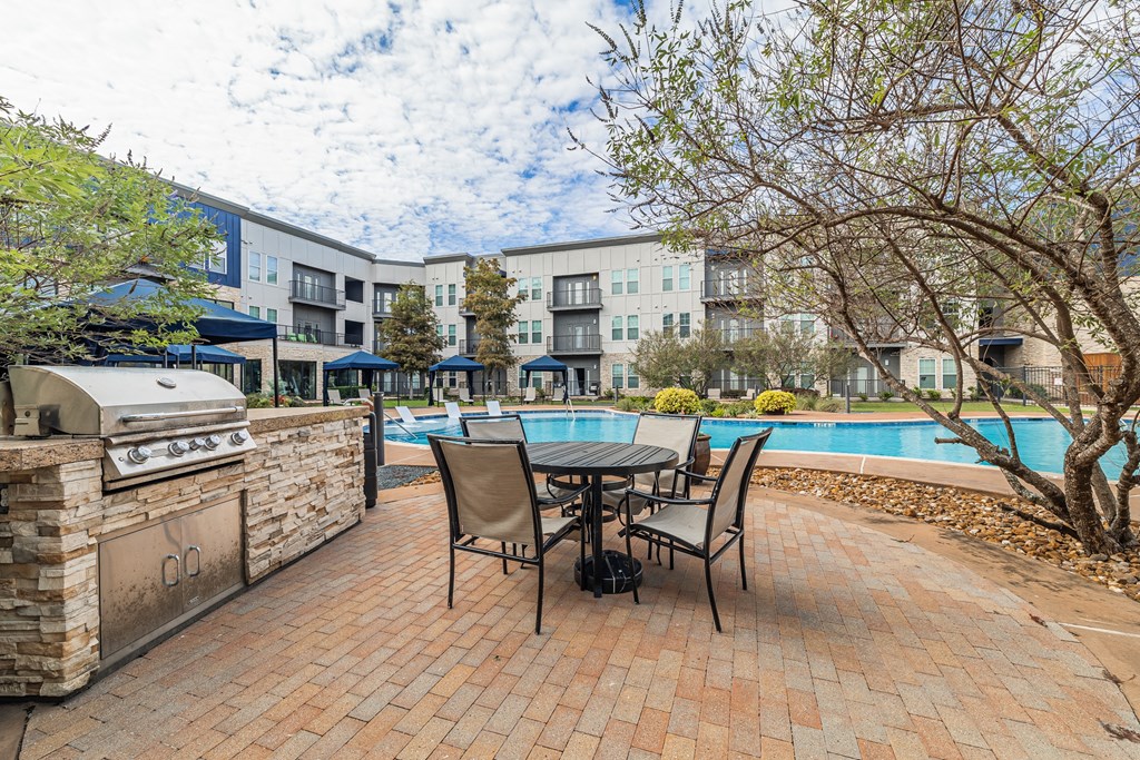 a patio with a table and chairs next to a swimming pool