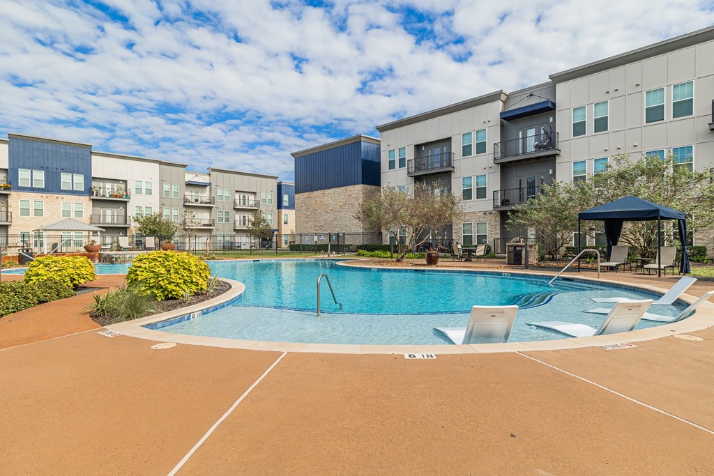 a swimming pool at an apartment complex with chairs around it