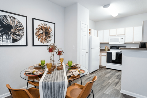A modern kitchen with a dining table set for two.