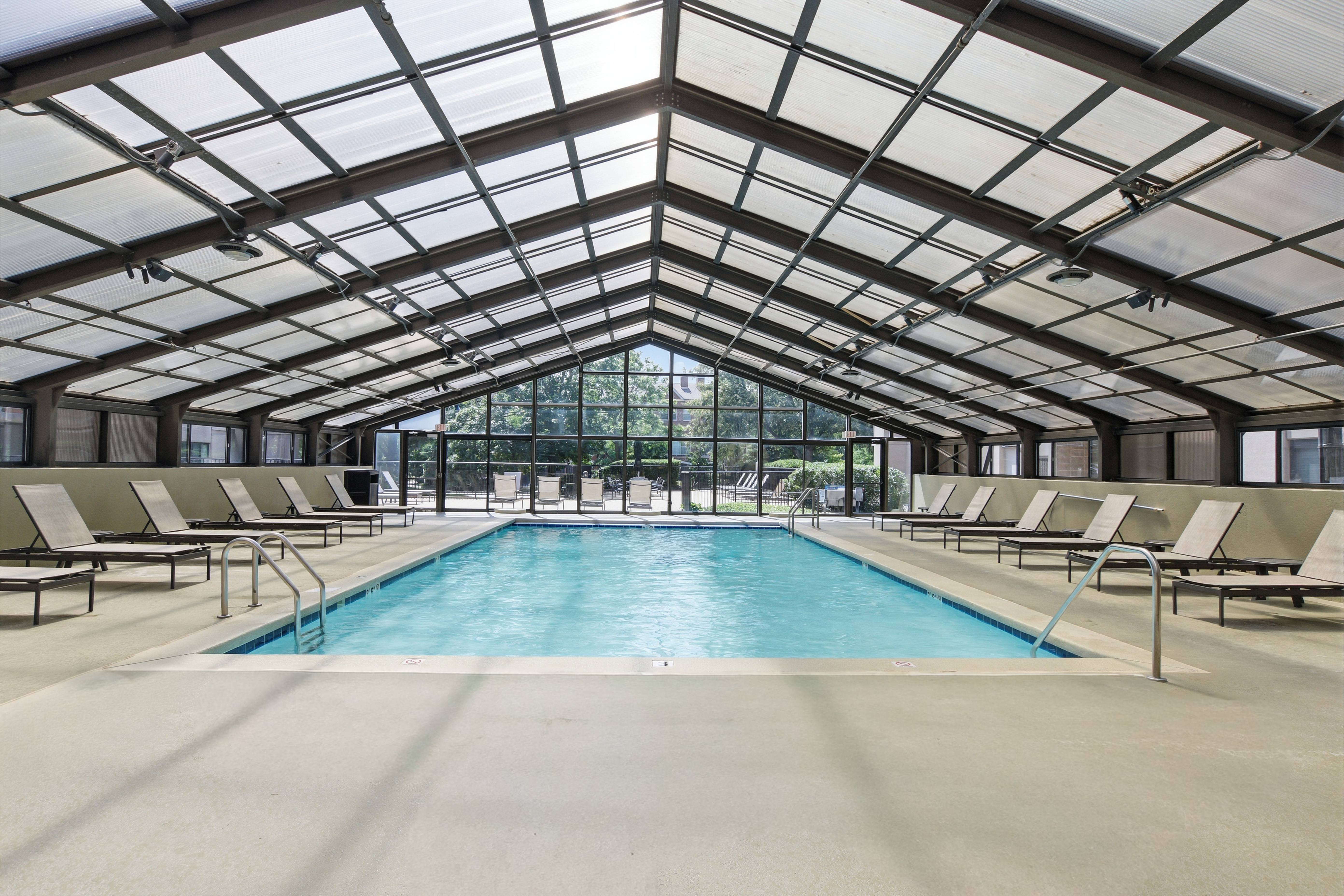 A large indoor swimming pool with sunroof and lounge chairs.