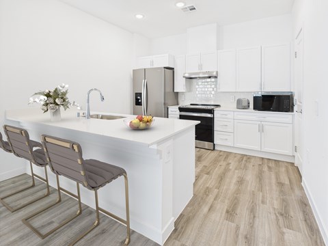 A kitchen with white cabinets and a wooden floor.