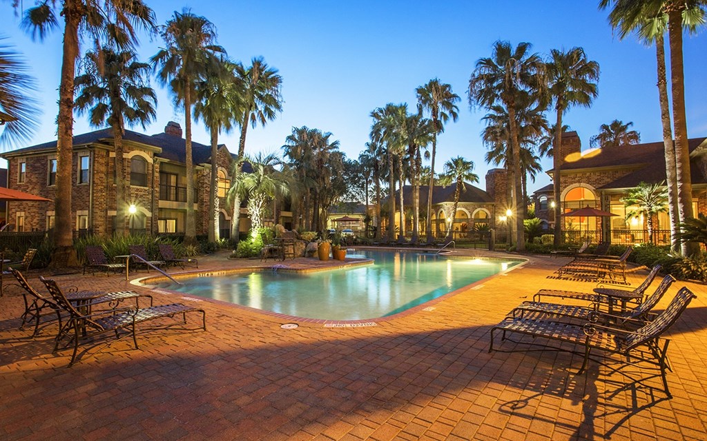 a swimming pool at night with palm trees