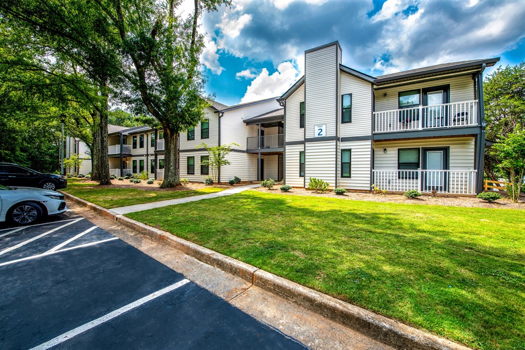 A car is parked on the left side of a street in front of apartment buildings.