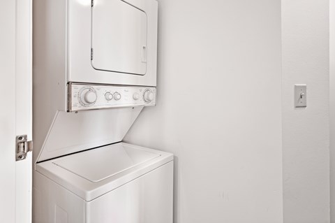 A white oven with a door open is in a room with a white wall.