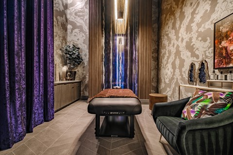 a living room with purple curtains and a massage table