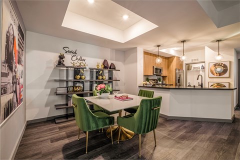 A dining area with a white table and green chairs.