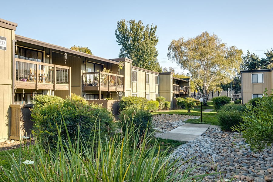 a street view of an apartment building with a pathway and landscaping