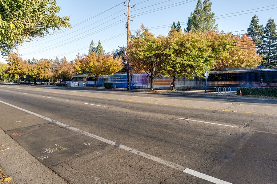 A street with a bus stop and trees in the background.