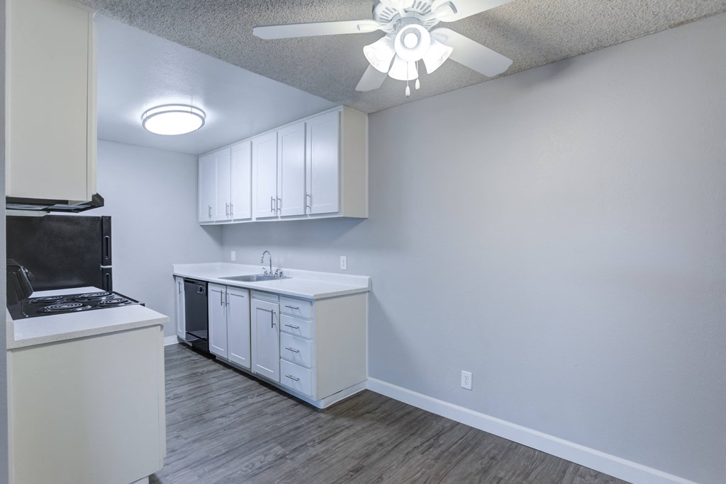 A kitchen with white cabinets and a black fridge.