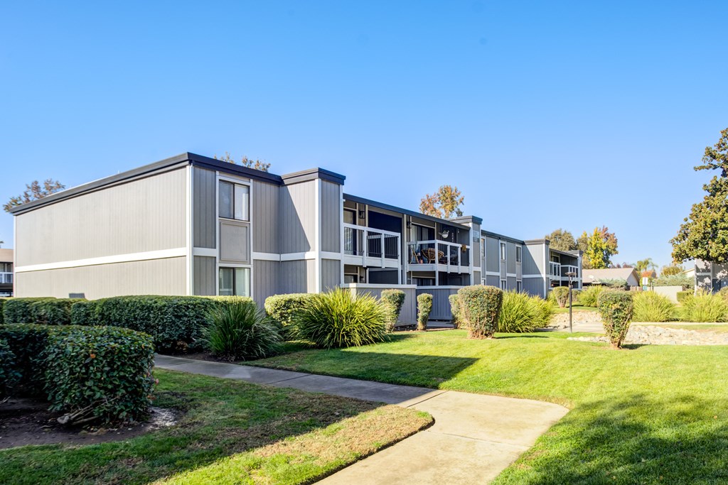 A modern building with a grey facade and a green lawn in front.