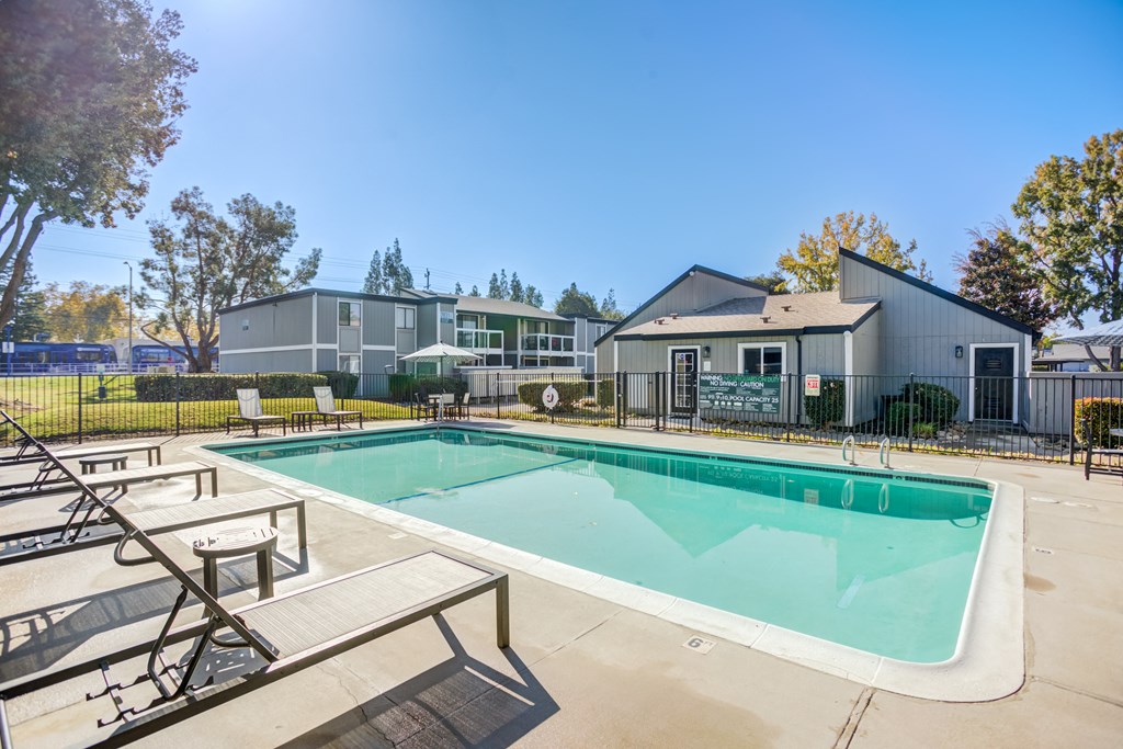 A swimming pool with a bench and a building in the background.