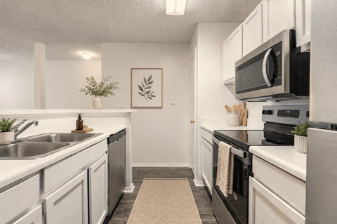 A kitchen with white cabinets and black countertops.