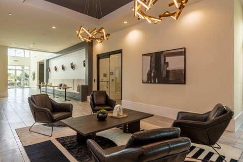 A modern living room with black leather chairs and a wooden coffee table.