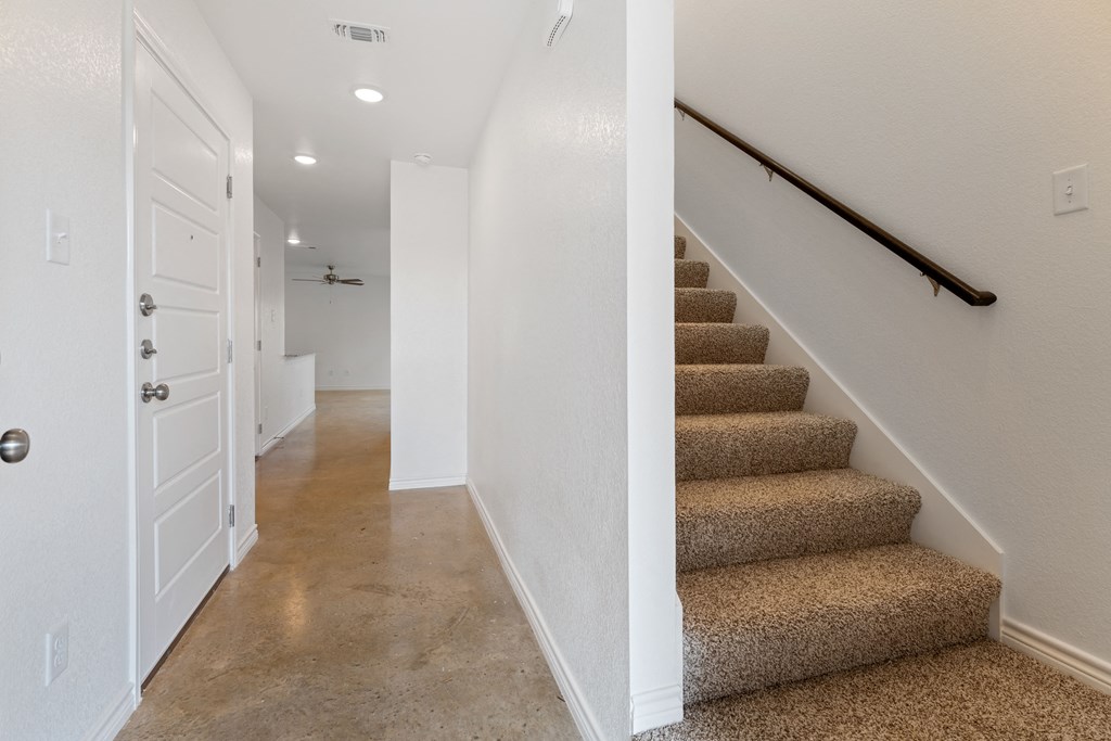 the landing of a staircase in a home with carpeted stairs and a white door