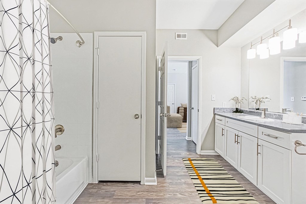 a bathroom with white cabinets and a shower and a sink