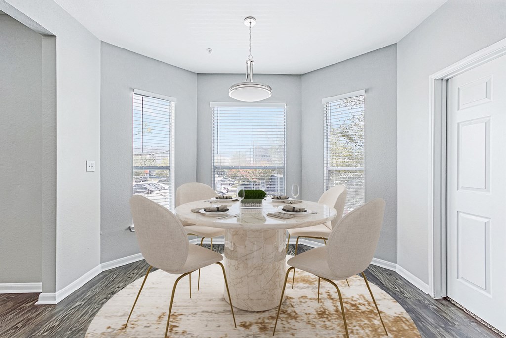 a dining room with a table and chairs and three windows