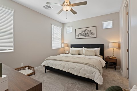 A bedroom with a large bed and a ceiling fan.
