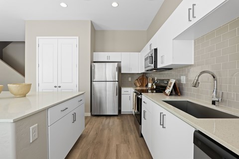 A modern kitchen with white cabinets and a stainless steel refrigerator.