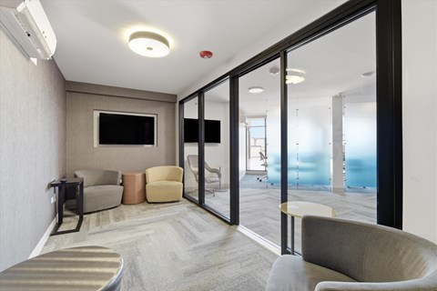 A living room with a television and a glass door leading to a balcony.