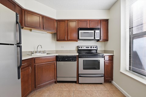 A kitchen with brown cabinets and a black refrigerator.