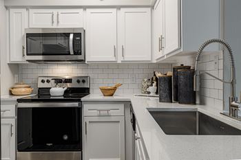 a kitchen with white cabinets and a stove and a microwave