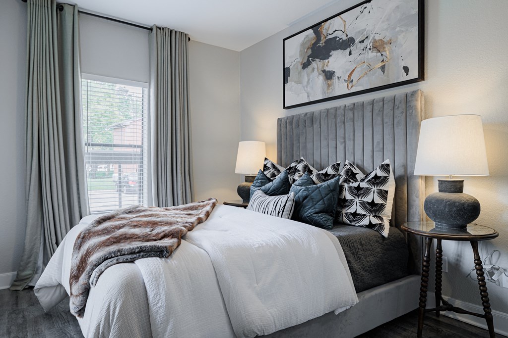 a bedroom with a large bed with pillows and a grey headboard