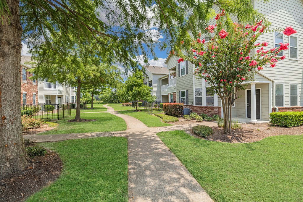 a walkway between two apartment buildings with trees and grass