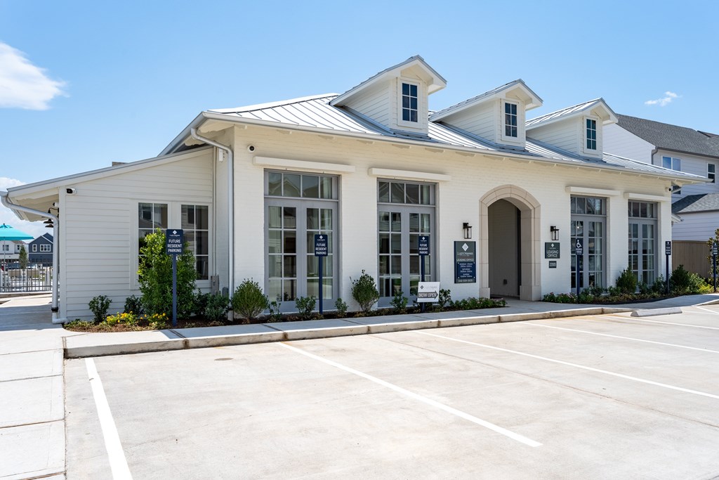 A white building with a parking lot in front.