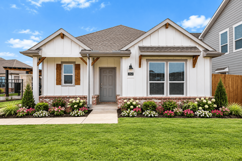 A house with a grey front door and windows surrounded by a green lawn.
