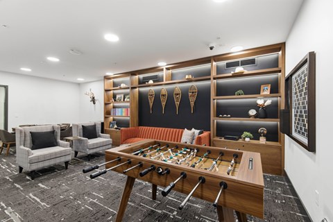 A shiny wooden pool table is in the middle of a room with a black and white carpet.