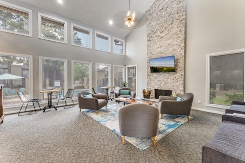 A living room with a stone fireplace and a television mounted above it.