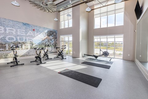 A gym with a brick wall that says "Break Out" and exercise equipment.