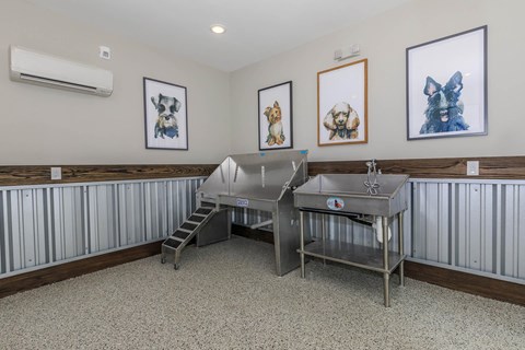 A room with a metal table and three framed pictures on the wall.