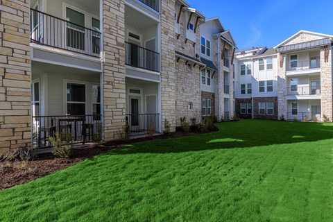 A row of apartment buildings with balconies and green lawns.