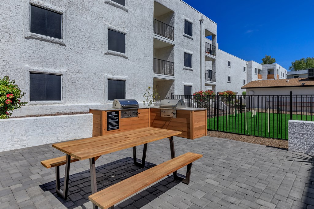 furnished patio with picnic table and grilling area at vela on the avenue apartments