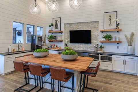 A kitchen with a wooden table and chairs, a brick backsplash, and a TV above the island.