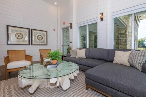 A living room with a glass table and grey couch.