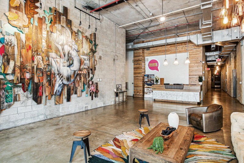 A room with a large mural on the wall and a variety of seating options.