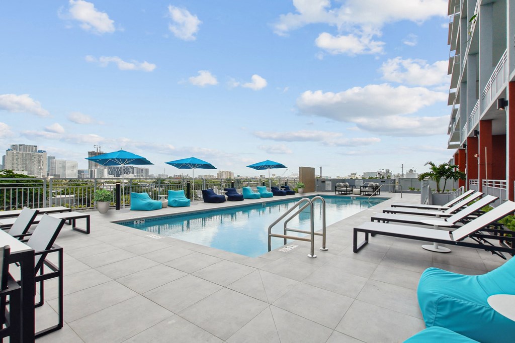 the pool on the rooftop of a building with blue umbrellas