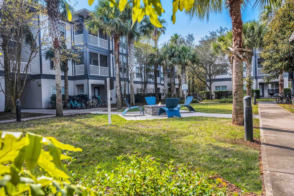a yard with a picnic table and chairs in front of an apartment building