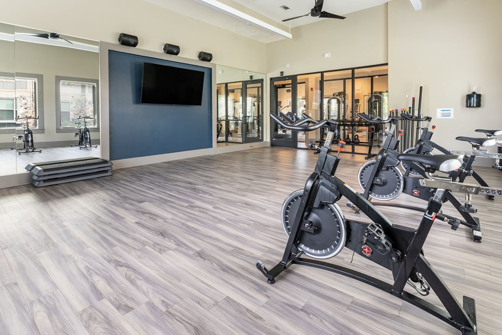 a gym with cardio equipment and a flat screen tv