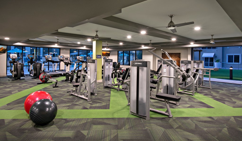 a gym with cardio equipment and weights in a building with blue walls