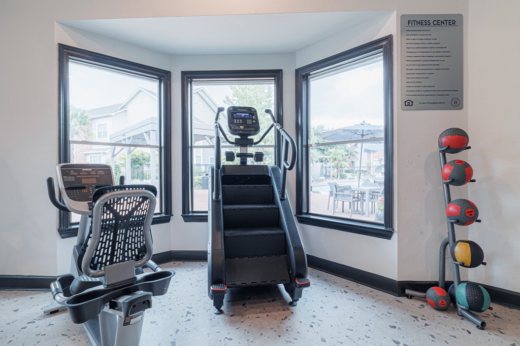 A fitness center with a treadmill, exercise balls, and a weight bench.