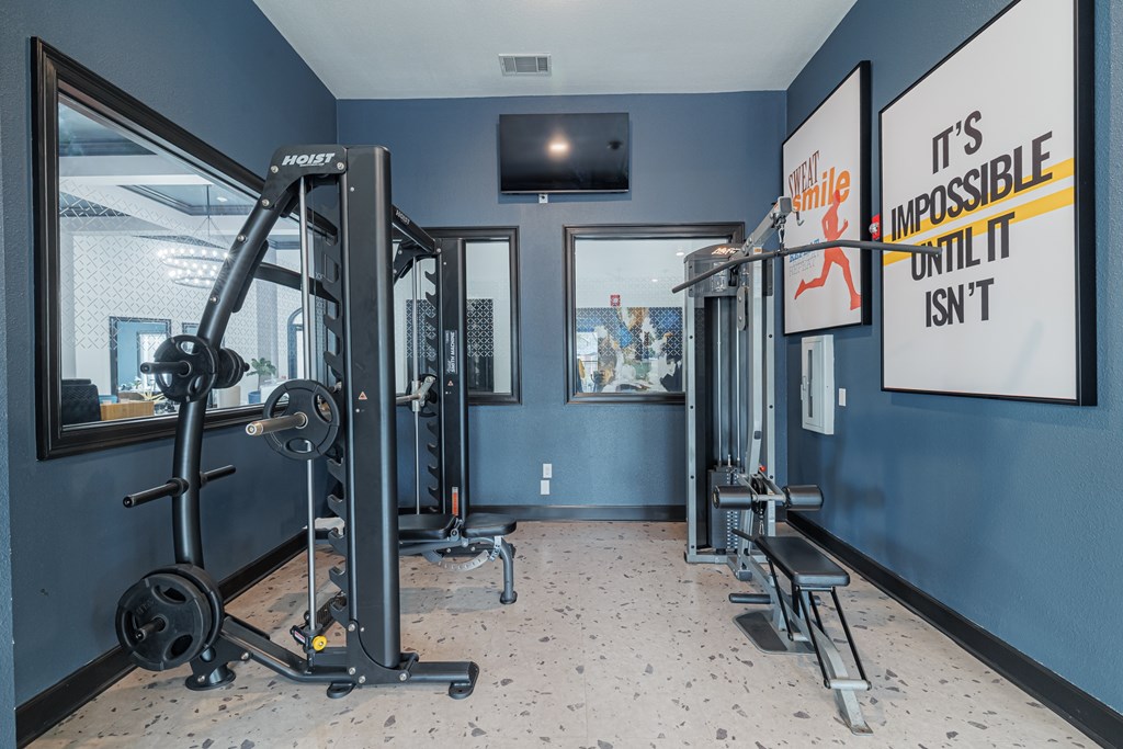 A gym with a mirror, weight machines, and a motivational poster.