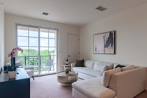 A living room with a large window and a painting on the wall.
