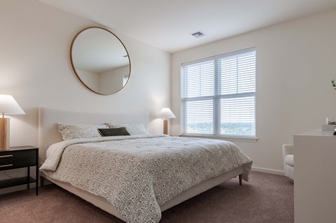 A bedroom with a round mirror on the wall.