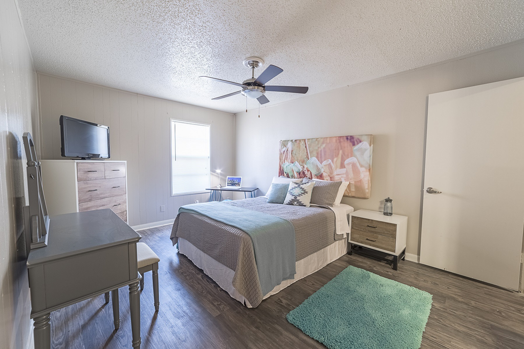a bedroom with a bed and a ceiling fan and a tv