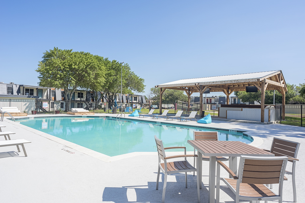 a swimming pool with chairs and tables next to a resort style pool