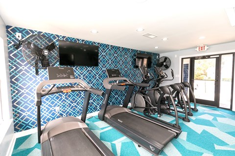 A gym with a treadmill, elliptical trainer, and other exercise equipment.